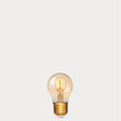 Dulora 4W Vintage Fancy Round LED Bulb E27 in Ultra Warm White glowing with deep amber warmth through tinted glass