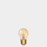 Dulora 4W Vintage Fancy Round LED Bulb E27 in Ultra Warm White glowing with deep amber warmth through tinted glass